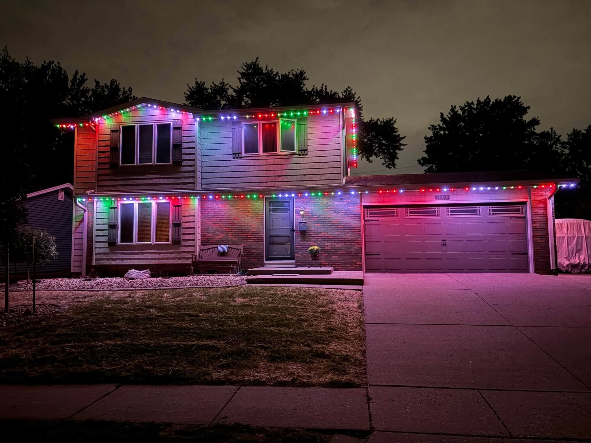 Two-story home with red and green holiday lights along roofline and garage